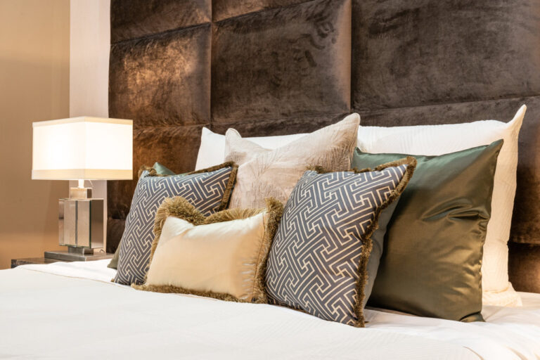Slaapkamer met hoog wandpaneel achter het bed en zachte kussens